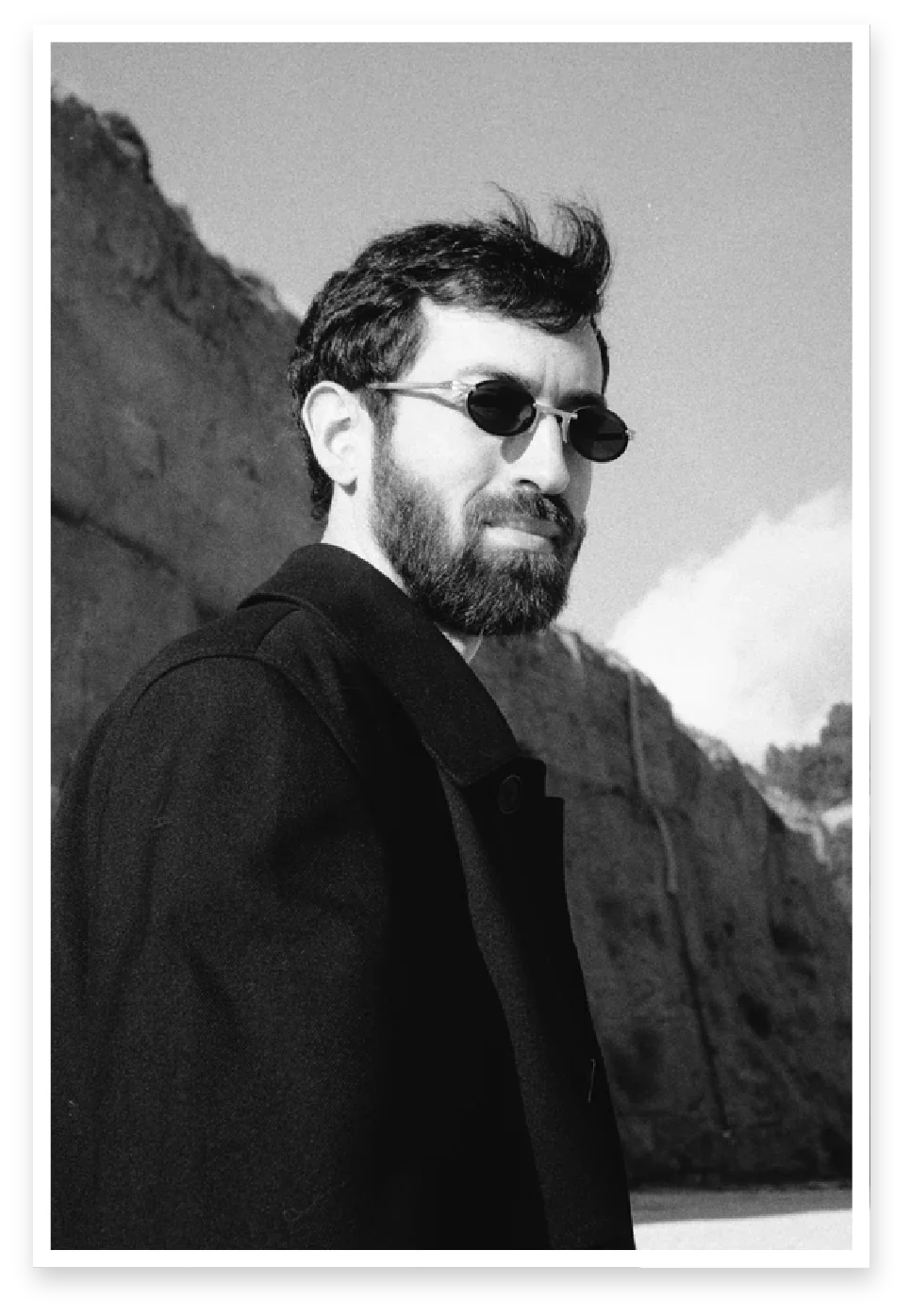 Rodion Sorokin in sunglasses against a cliff, black and white